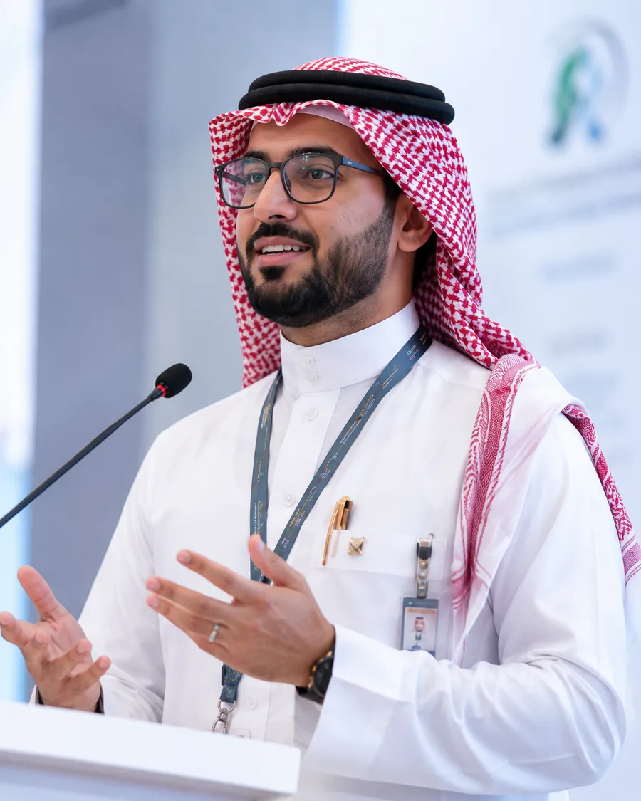 Saudi healthcare leader speaking at a conference podium
